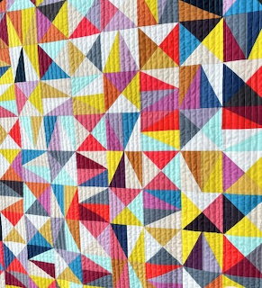 Colorful patchwork quilt with geometric triangle pattern in multiple bright colors