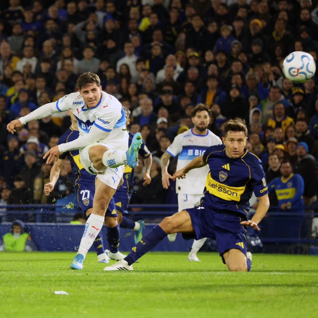 Soccer player in white jumps to head ball during crowded stadium match at night
