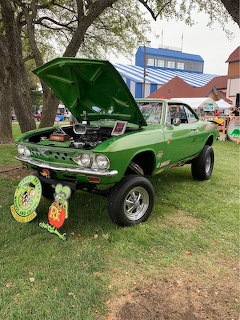 Bright green 1967 Chevrolet Corvair with open hood parked on grass at a car show