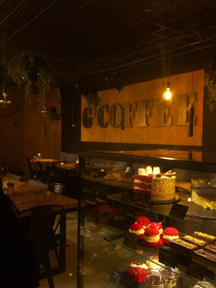 Cozy café interior with dessert display case, warm lighting, and G'COFFEE sign on dark wall