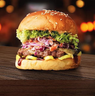 Close-up cheeseburger with lettuce, onions, pickles, and melted cheese on a wooden table