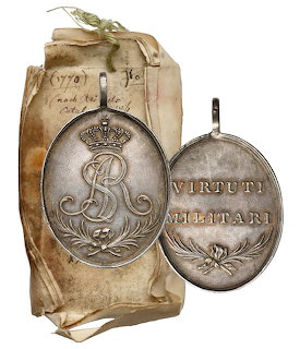 Silver oval Virtuti Militari medal with crowned cipher and engraved text on aged paper