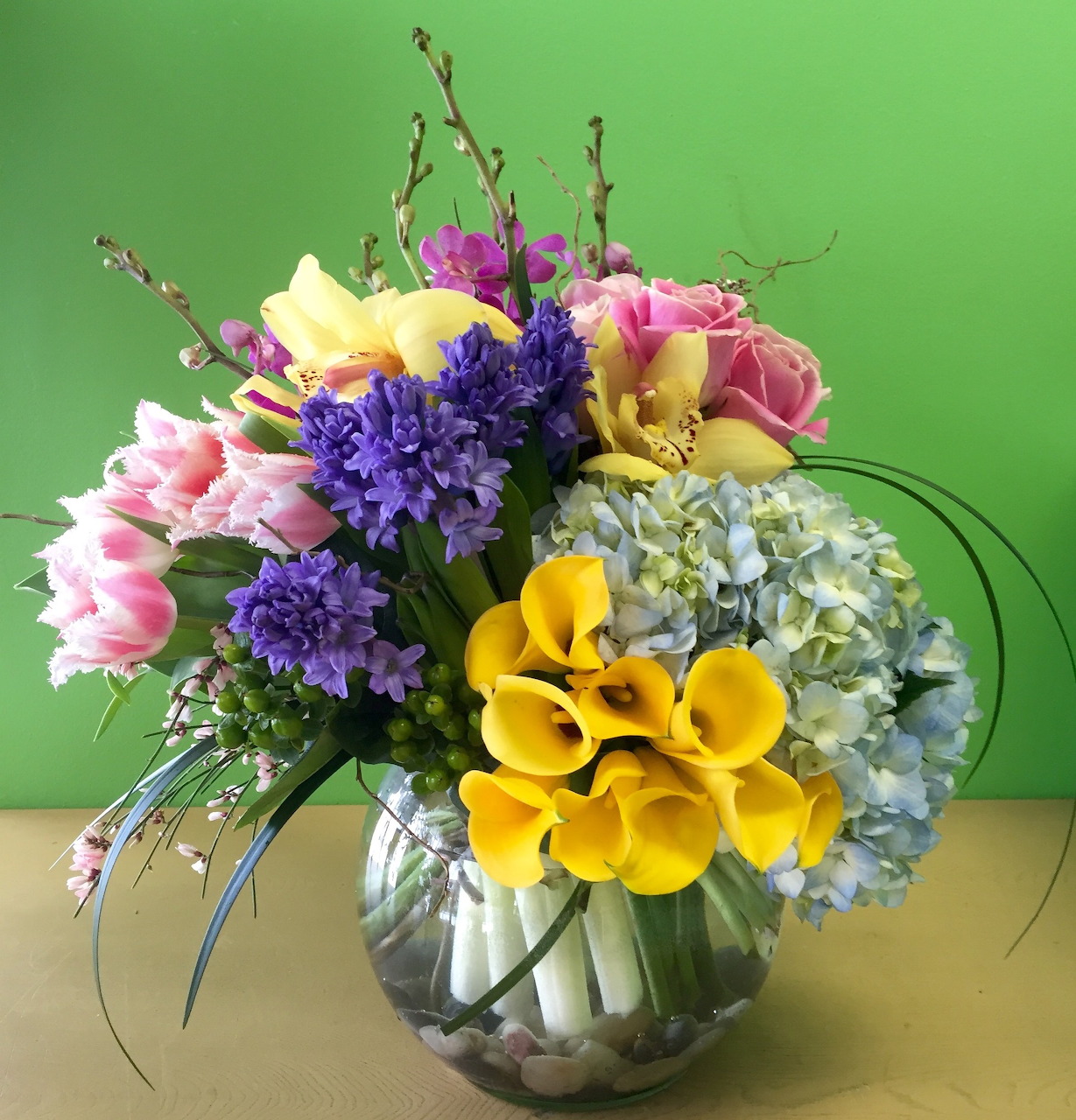 Colorful spring flower arrangement with yellow calla lilies, purple hyacinths, pink tulips in glass vase