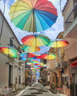 Colorful umbrellas hanging above a narrow street between buildings
