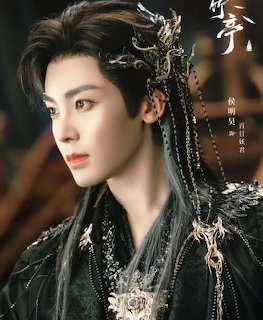 Young man in ornate traditional Chinese costume with decorative black headdress and silver ornaments