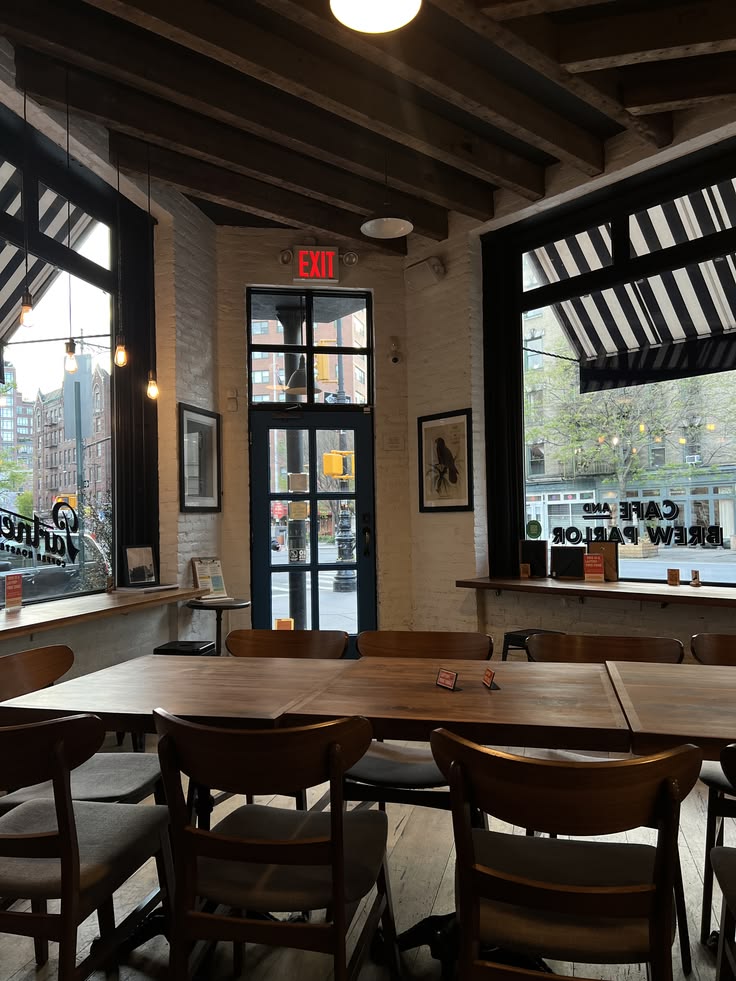 Cafe interior with wooden tables and chairs, exposed brick walls, black-framed windows and dark ceiling beams