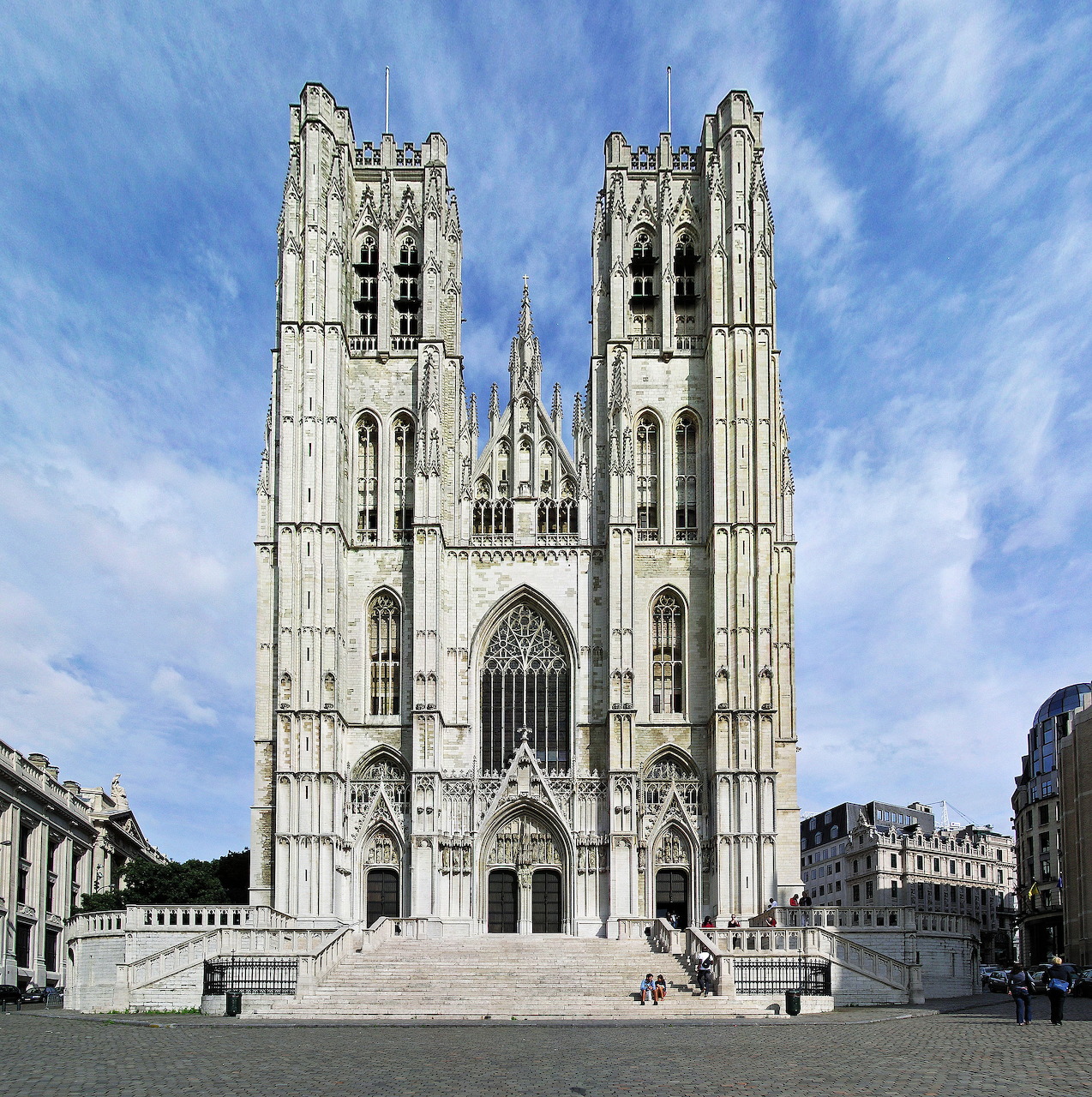 Gothic cathedral with twin towers and ornate facade under a blue sky with clouds in Brussels