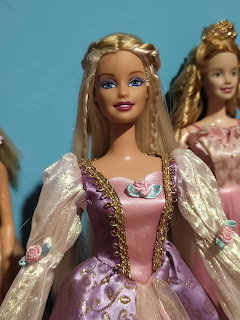 Blonde Barbie doll in pink and purple Rapunzel princess gown with another Barbie doll behind