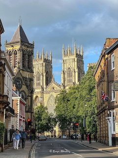 York Minster towering above a quiet street lined with historic buildings and trees