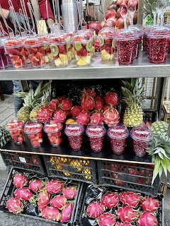 Market fruit stall with fruit cups, dragon fruit, pineapples, and pomegranate seed cups
