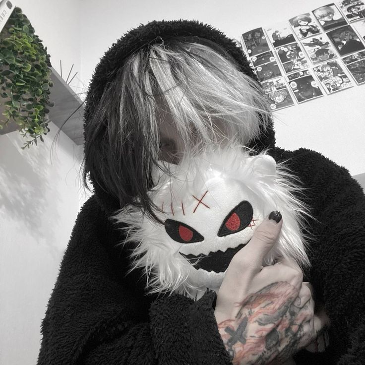 Person with dyed hair hugging a fluffy white monster plush indoors