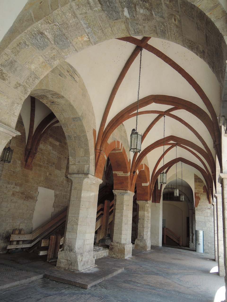 Historic stone interior with vaulted arches, columns, and a tiled corridor