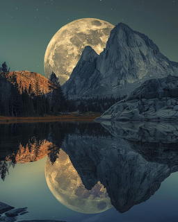 Full moon rising behind rocky mountain peaks with perfect reflection in a calm alpine lake at night