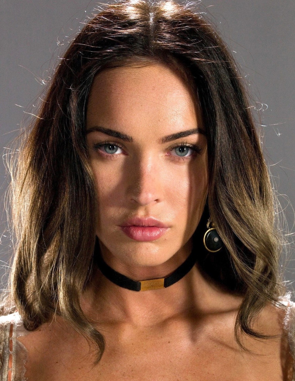Close-up portrait of a woman with blue eyes, ombre hair, black choker, and hoop earring