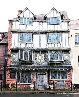 Historic Tudor timber-framed house with black and white facade and ornate leaded windows in Exeter, Devon