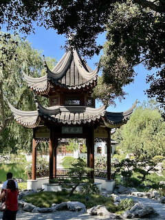 Traditional Japanese pagoda with curved roof in garden with pond and trees
