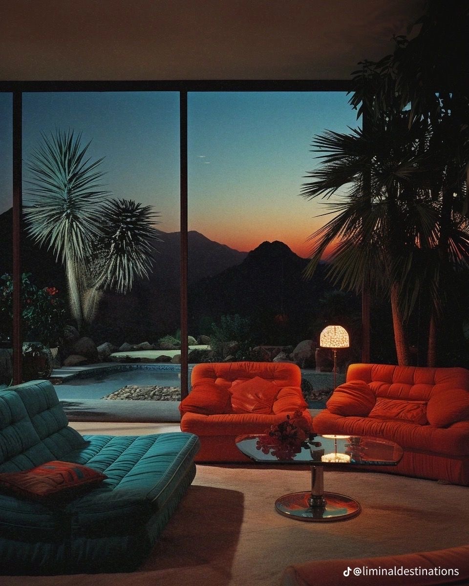 Modern living room with orange sofa, turquoise chairs, and sunset mountain view through large windows