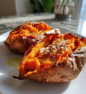 Two halves of a baked sweet potato topped with seasoning on a white plate