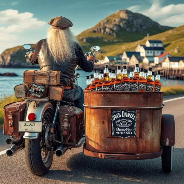 Vintage motorcycle with a side trailer of whiskey bottles beside a coastal village and mountain