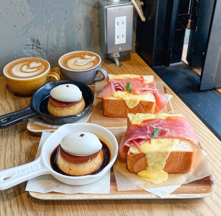 Cafe table with latte art drinks, custard puddings, and thick toast topped with ham, cheese, and fruit