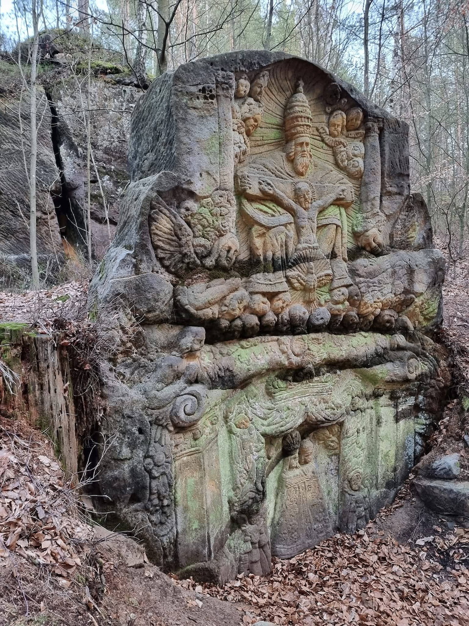 Weathered stone Buddha statue in meditation pose carved into rock formation in forest