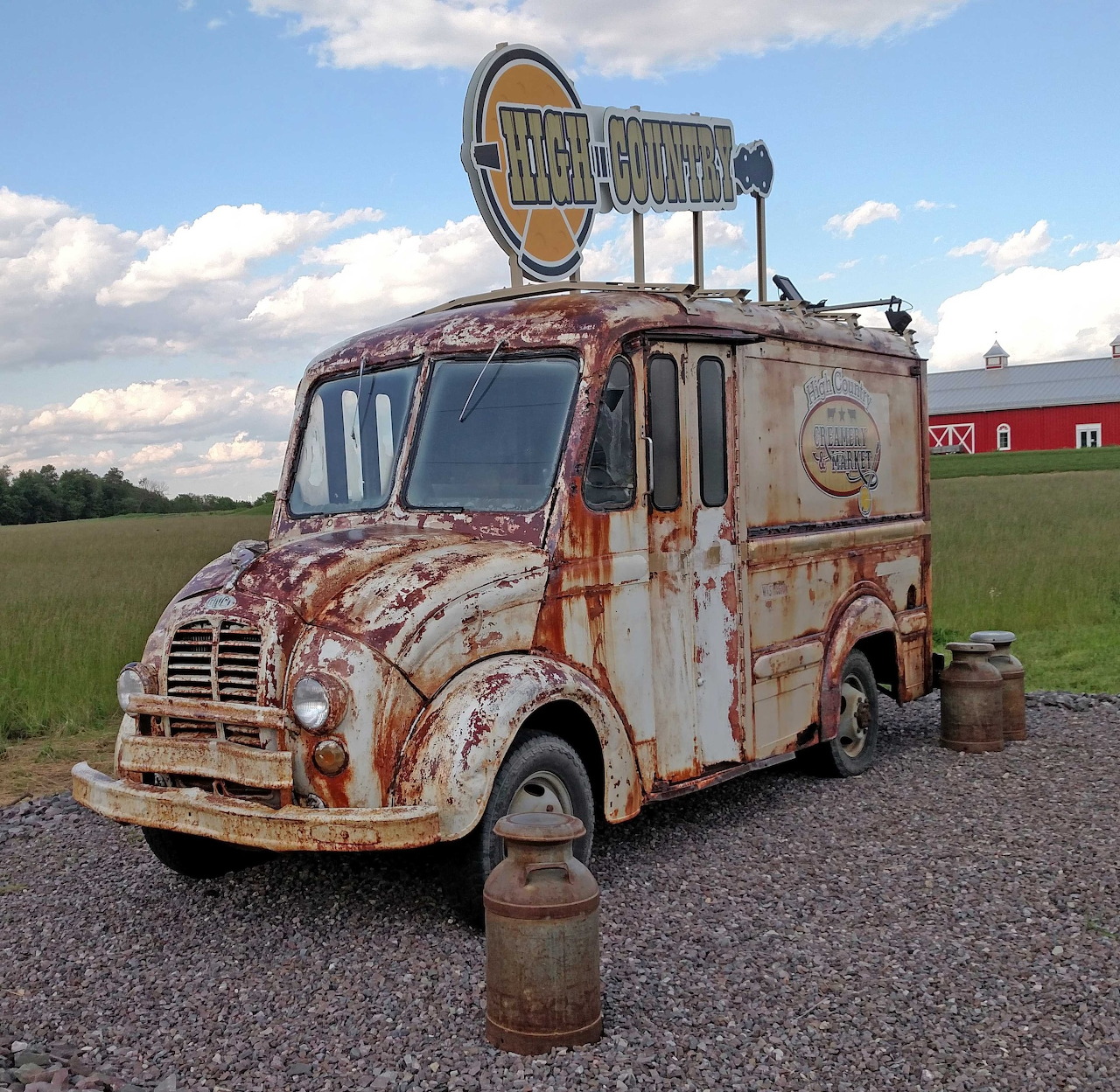 Rusty vintage Divco milk delivery truck with sign on top parked in rural field