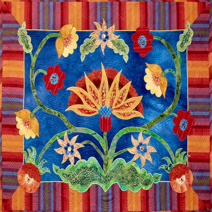 Ornate quilt block featuring golden lotus and star flowers with green leaves on deep blue, surrounded by multicolor stripes
