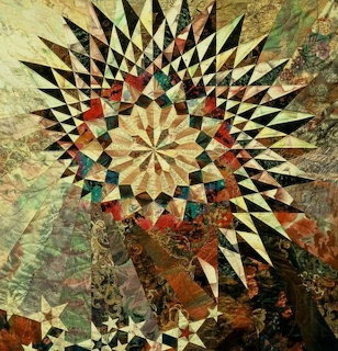 Star quilt with radiating geometric pattern in black, cream, and earth tones with patchwork border