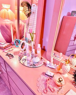 Pink vanity table with mirror, cosmetics, candles, and feminine accessories in a shaby chic bedroom