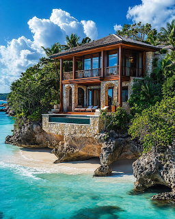 Two-story stone villa with wooden balconies on a rocky cliff above a turquoise tropical beach