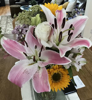 Mixed flower bouquet featuring pink lilies, white roses, yellow sunflower and green foliage