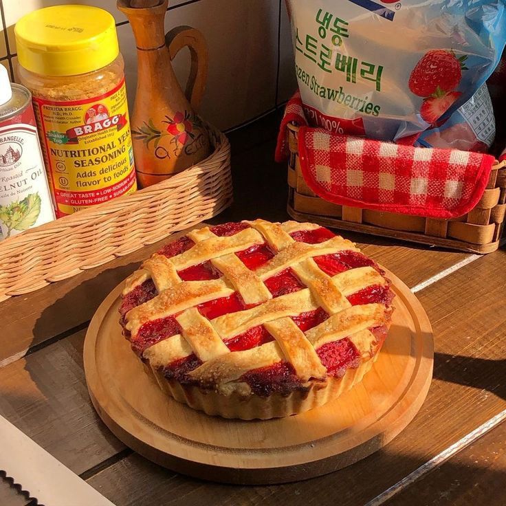Cherry pie with lattice crust on wooden serving board in kitchen setting