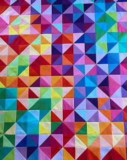 Colorful quilt with geometric triangle and square patterns in bright rainbow colors