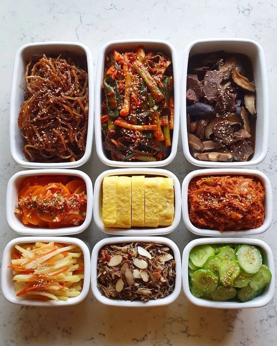 Nine white bowls arranged in a 3x3 grid, each containing a different Korean banchan side dish