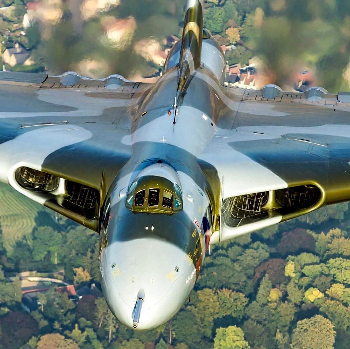 Avro Vulcan bomber aircraft flying over green countryside seen from above