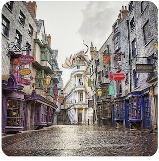 Cobblestone street with colorful shop fronts and a dragon sculpture on a white building at the end