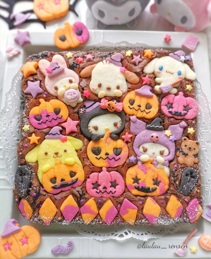 Square chocolate cake decorated with Hello Kitty cookies in pumpkin, ghost, and monster costumes with Halloween candy