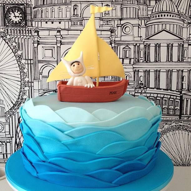Decorated cake with character in yellow sailboat on blue ruffled waves against drawn Venice buildings