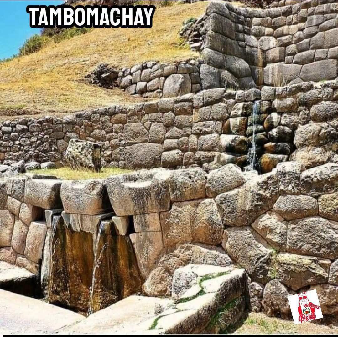 Stone ruins and water channels at Tambomachay with dry grass and blue sky