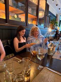 Two women seated at a restaurant table, one holding a sparkler, with wine glasses and place settings