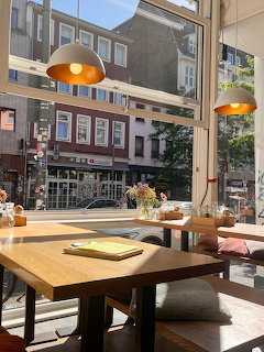 Wooden table beside large café window overlooking city street with orange pendant lights above