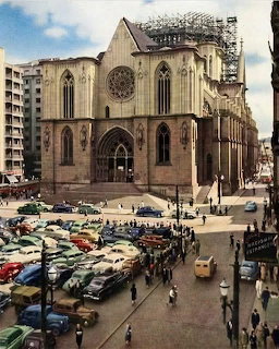 Gothic cathedral with rose window and pointed arches in urban plaza with vintage cars
