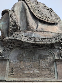 Close-up of an ornate bronze statue base with engraved relief panels