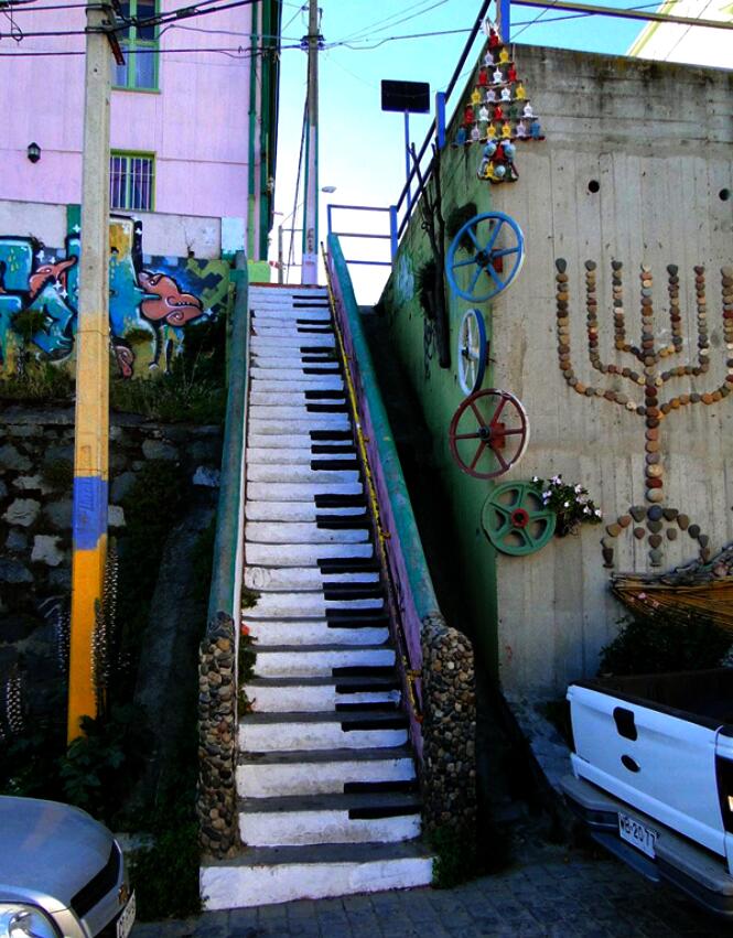 Outdoor staircase painted as piano keys with murals and bicycles on nearby walls