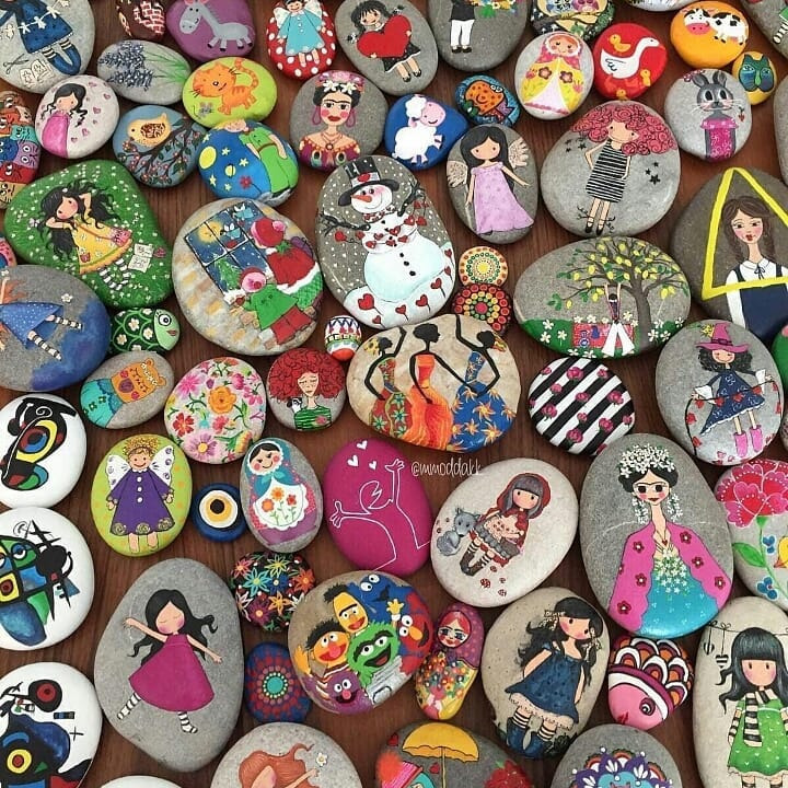 Assorted colorful painted pebbles with dolls, flowers, birds, and decorative patterns