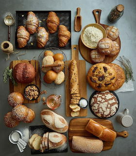 Assorted artisan breads, croissants, and pastries displayed on wooden cutting boards from above
