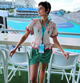 Woman standing on a balcony overlooking a racetrack in casual summer clothes