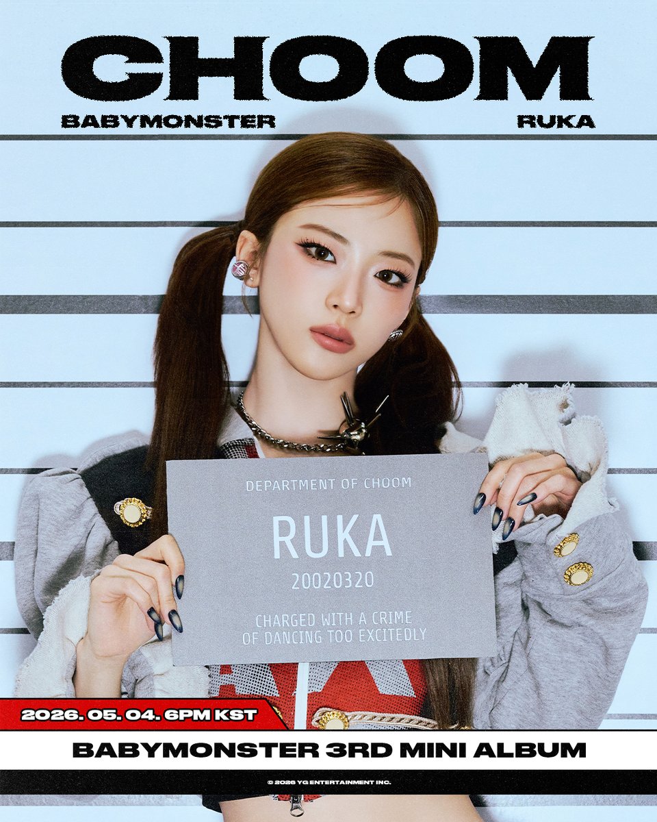Ruka of BabyMonster holding a CHOOM name placard in a K-pop promotional photo