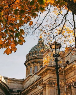 Cathedral dome framed by orange autumn leaves with a vintage street lamp in the foreground