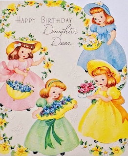 Vintage birthday card with four girls in dresses holding flowers, framed by yellow roses and floral decorations